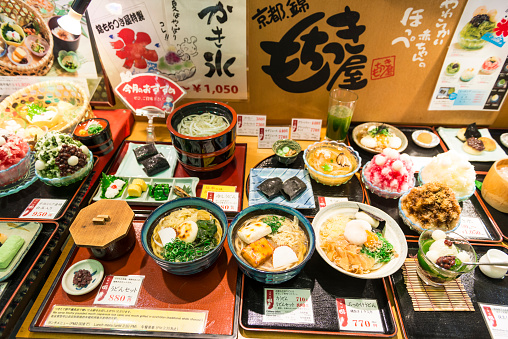 Kyoto, Japan - August 12, 2014: Varieti of prepared Japanese food served in different bowls and plates with insriptions with price and ingredients. The food is exposed in front of a restaurant and look very colorful. Top view.