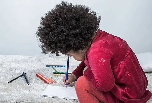 Photo of Cute african girl drawing with pencil