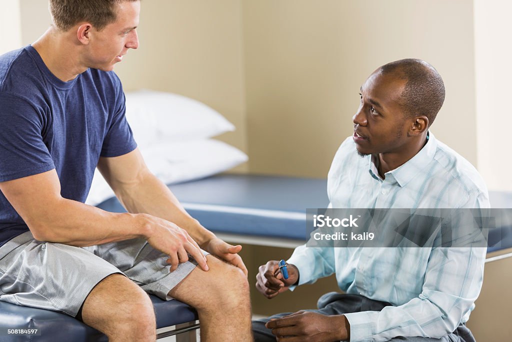 Physical therapist examining patient Physical therapist examining patient, testing reflexes with reflex hammer. Examining Stock Photo