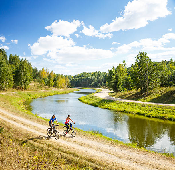 Young Happy Couple Riding Bicycles by the River stock photo