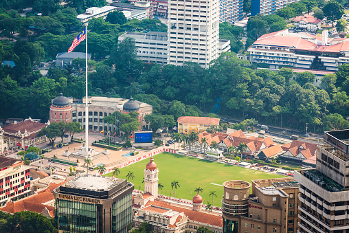 Aerial view through the skyscrapers of downtown Kuala Lumpur to the green lawn of Merdeka Square, the landmark Sultan Abdul Samad Building and Malaysia's National Flag, the historic heart of Malaysian independence. ProPhoto RGB profile for maximum color fidelity and gamut.