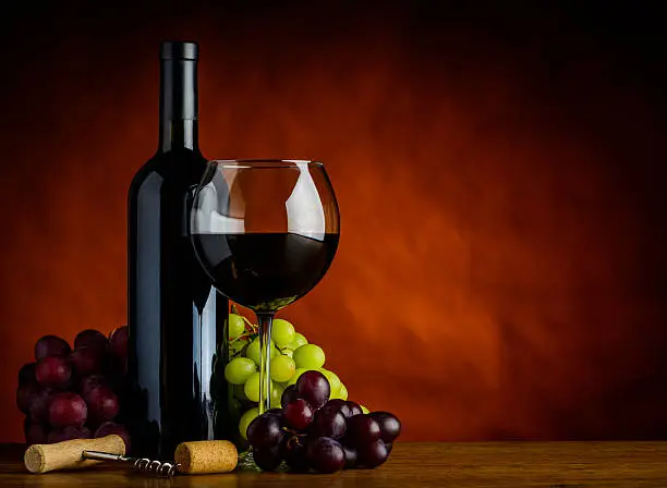 Bottle and Glass of red Wine with grapes in still life with Copy-Space
