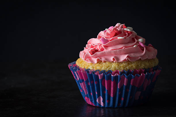istock Single Cupcake and Pink Frosting on Table with Dark Background 508192218