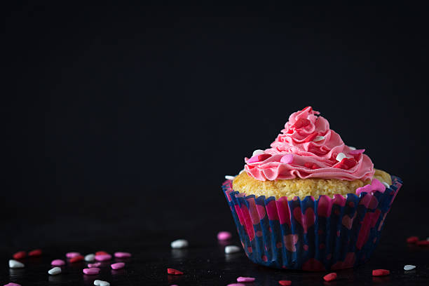 Cupcake with swirls of creamy strawberry frosting on white background Macro