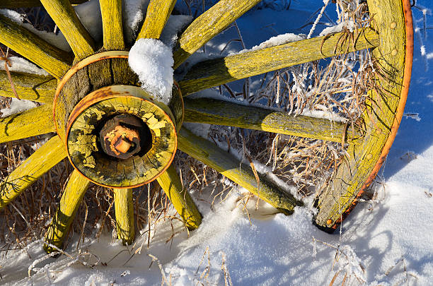 Old Yellow Wheel A close up image of an old yellow wagon wheel covered in snow and frost. covered wagon horse cart snow winter stock pictures, royalty-free photos & images