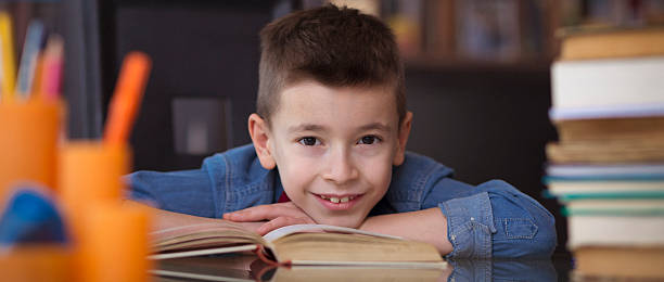 Little boy possing for the camera while doing homework stock photo