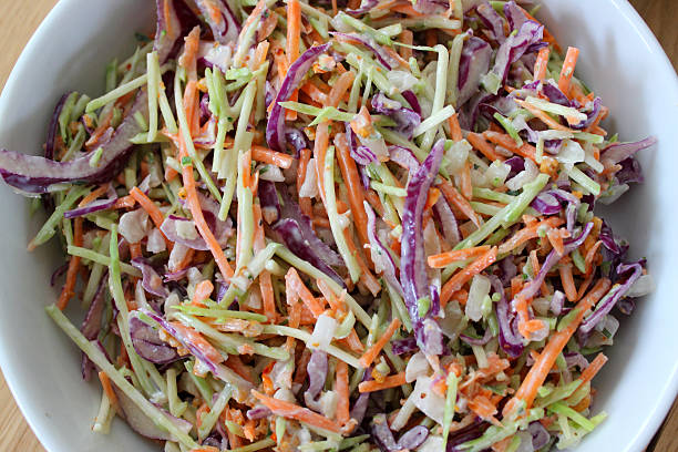 Homemade coleslaw, shredded red cabbage, grated carrot, sliced onion, mayonnaise Photo showing a white dish of homemade coleslaw, made with shredded red cabbage, grated carrot and slices of mild Spanish sliced onion, mixed with a generous amount of low-calorie mayonnaise. coleslaw stock pictures, royalty-free photos & images