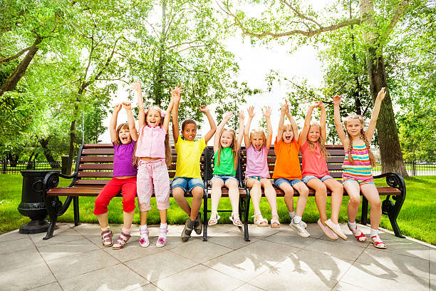 istock Excited kids with arms and sit in row on bench 508201359