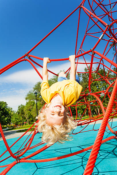 istock Smiling boy hangs upside down on rope of red net 508201399