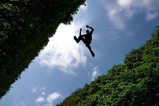 Man jumping over bushes against blue sky background