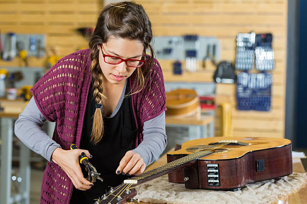 istock Woman changing guitar strings while working in instrument repair shop 508208472