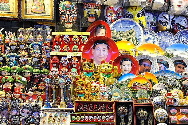 Beijing night market selling Xi Jinping face plates Beijing, China - October 19, 2014 - A souvenir stall at a Beijing night market selling Xi Jinping face plates and other kitsch rubbish. wangfujing stock pictures, royalty-free photos & images