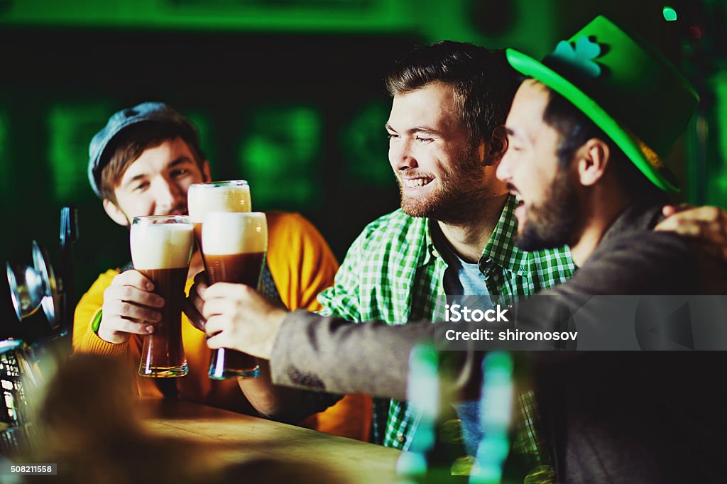 Celebration Happy guys with glasses of foaming beer spending time in pub St. Patrick's Day Stock Photo