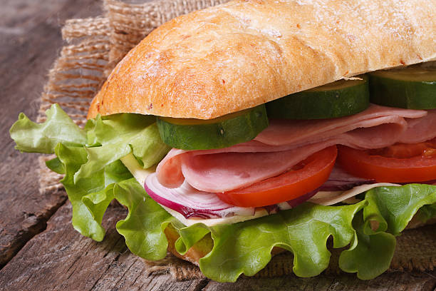 ciabatta sandwich au jambon et légumes macro sur la table. - bun salad ham rolled up photos et images de collection