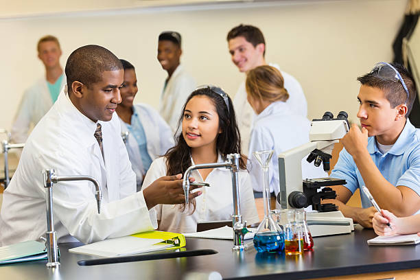 istock High school science teacher talking with students in chemistry lab 508213235