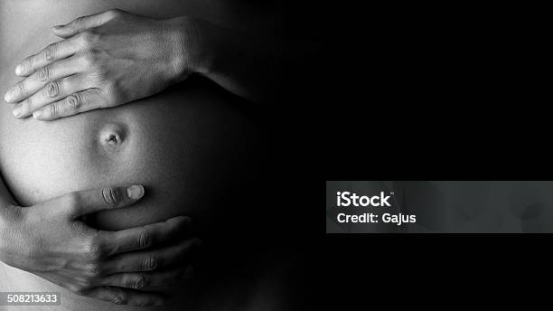 Expectant Mother Holding Her Belly In Lowkey Stock Photo - Download Image Now - Pregnant, Black And White, Human Abdomen