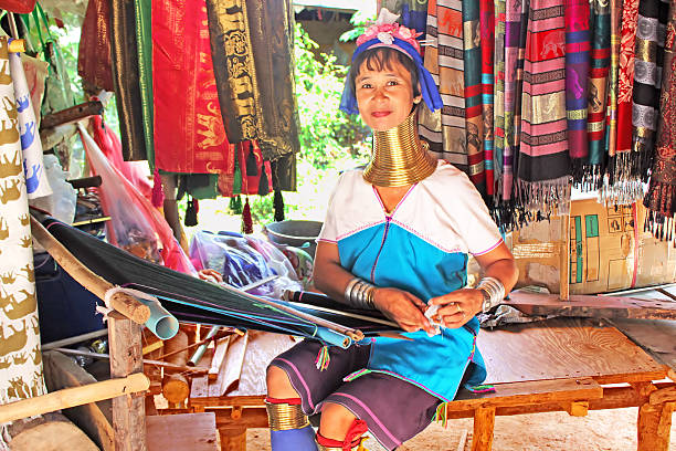 Unidentified Padaung (Karen) tribe woman weave on traditional device Mae Hong Son, Thailand - June 17, 2014: Unidentified Padaung (Karen) tribe woman weave on traditional device near Mae Hong Son, Thailand, Chiang rai, Karen Long Neck hill tribe village. Padaung women wear brass rings on the neck since the age of 5 years unidentified padaung karen tribe woman weave on traditional device stock pictures, royalty-free photos & images