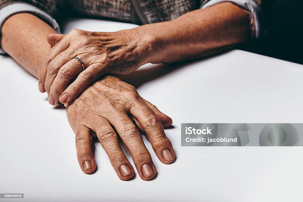 Niña con las manos sobre una mesa - Foto de stock de 70-79 años libre de derechos