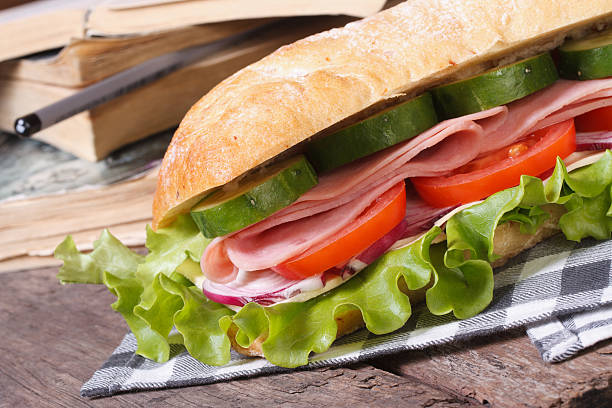 ciabatta z szynkę i warzywa na tle książek - bun salad ham rolled up zdjęcia i obrazy z banku zdjęć