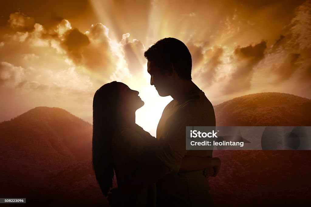 Young couple silhouette on a mountain Young couple silhouette on a mountain on sunset background Adult Stock Photo