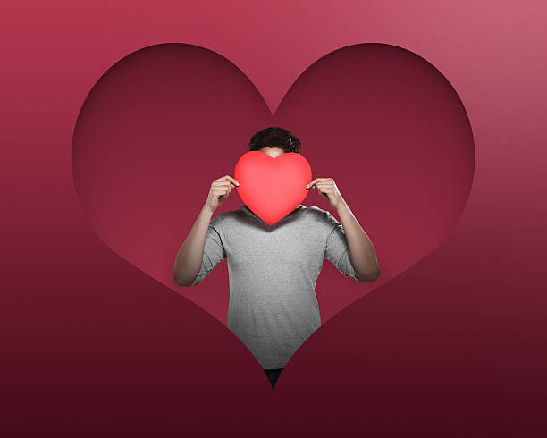 istock Handsome man holding red heart cover his face 508223158