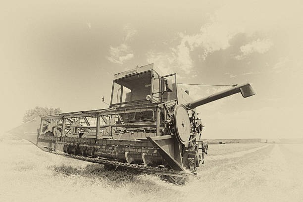 Old faded image of combine harvester parked in wheat field on summer day