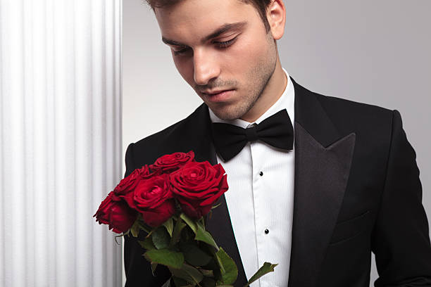 istock Elegant business man looking at a red roses bouquet 508224082