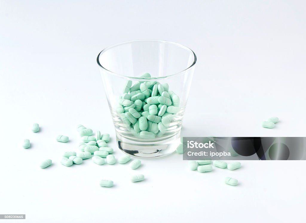 Pills in the glass Pills in the glass on blue tone background Addiction Stock Photo