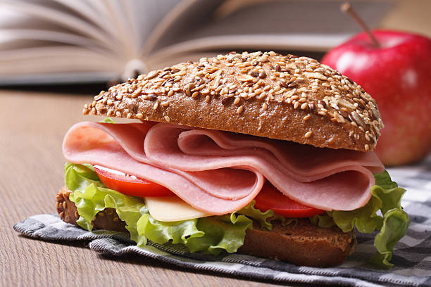 école déjeuner: un sandwich au jambon et gros plan de pommes - bun salad ham rolled up photos et images de collection