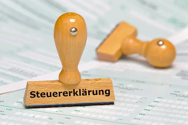 rubber stamp marked with tax declaration in german language - Steuererklärung - over documents and tax forms