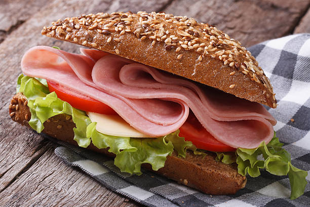 sandwich mit schinken, salat und tomaten auf einem alten tisch - sandwich submarine sandwich ham bun stock-fotos und bilder