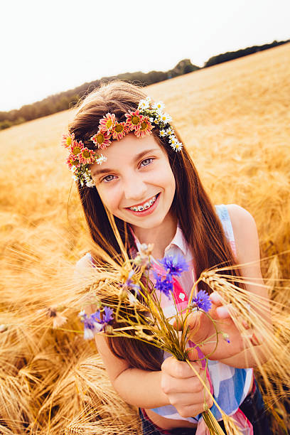 Young girl picking wild flowers in wheat field
