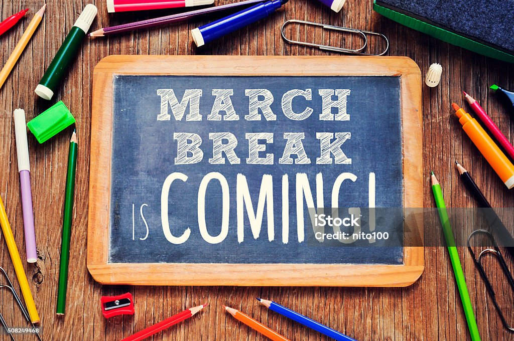 the text march break is coming written in a chalkboard high-angle shot of a rustic wooden table with some pencils and markers and a chalkboard with the text march break is coming written in it Chalkboard - Visual Aid Stock Photo
