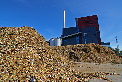 bio power plant with storage of wooden fuel (biomass) against blue sky