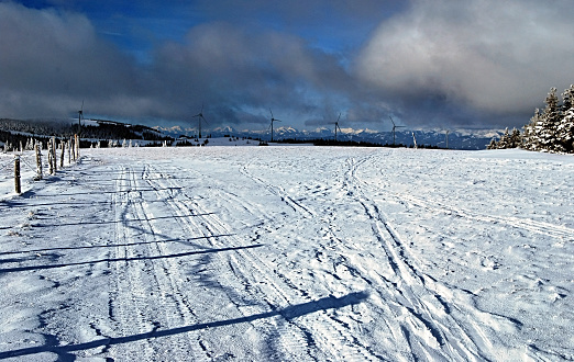 winter Fischbacher Alpen in Styria with Murzzuschlag - Pretul wind park turbines, panorama of higher peaks on the background and blue sky with clouds