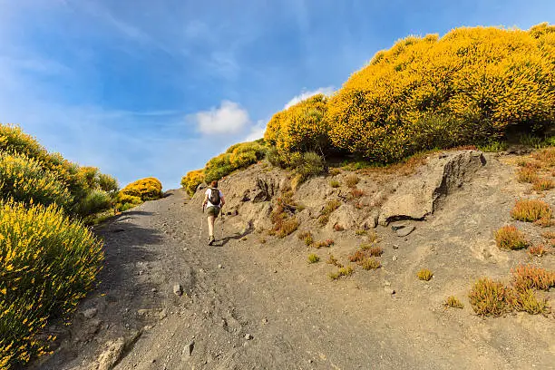 Woman hiking towards Vulcano in spring, in the island of the same name.  Aeolian archipelago, Sicily, Italy