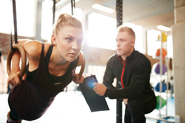 istock Woman with her personal trainer exercising on gymnastic rings 508259232