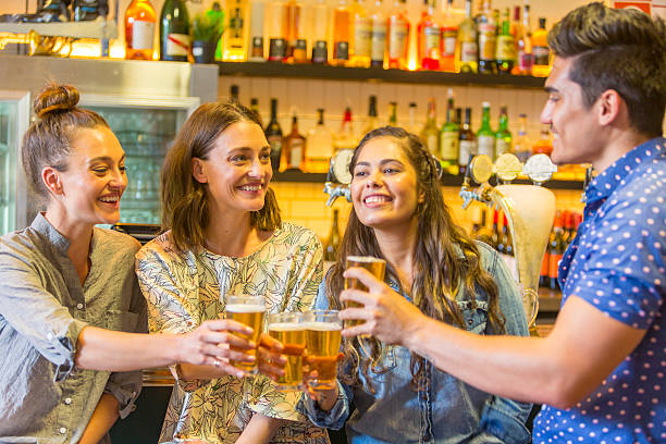 молодой человек праздничных с напитками и девушек в баре - australia aborigine group of people friendship стоковые фото и изображения