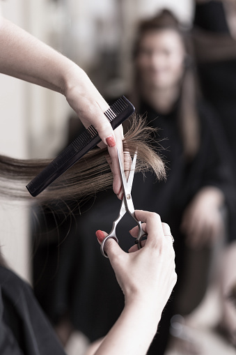 Closeup image of Processional Hairdresser's hands are cutting brown short hair with hair cutting Scissor