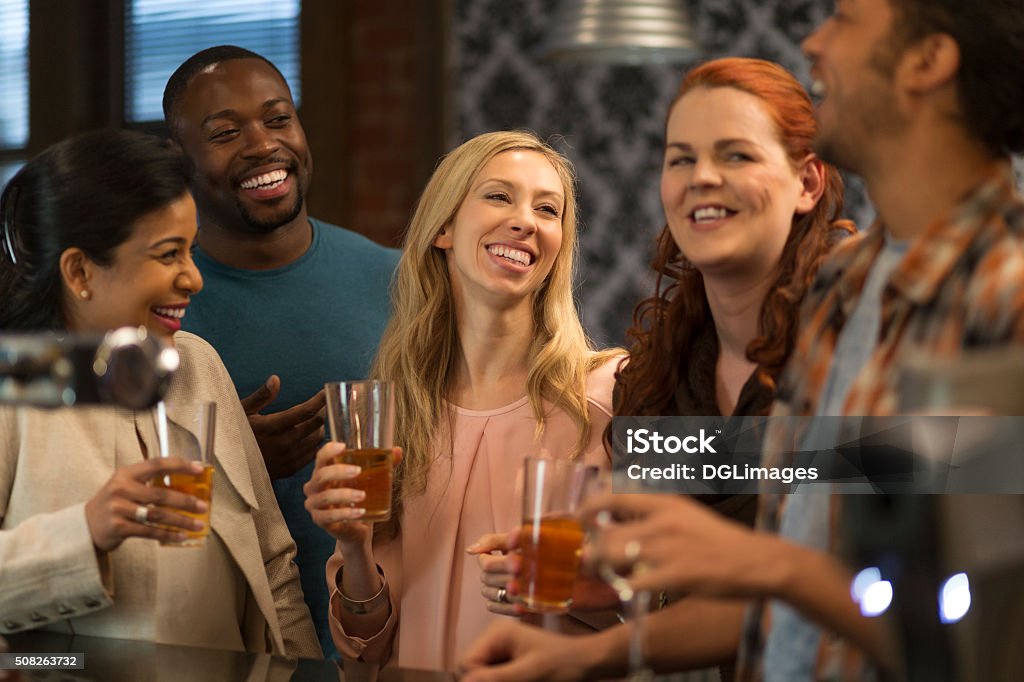 Friends at a bar Group of friends drinking beer at a bar. They are all laughing and talking to eachother. Adult Stock Photo