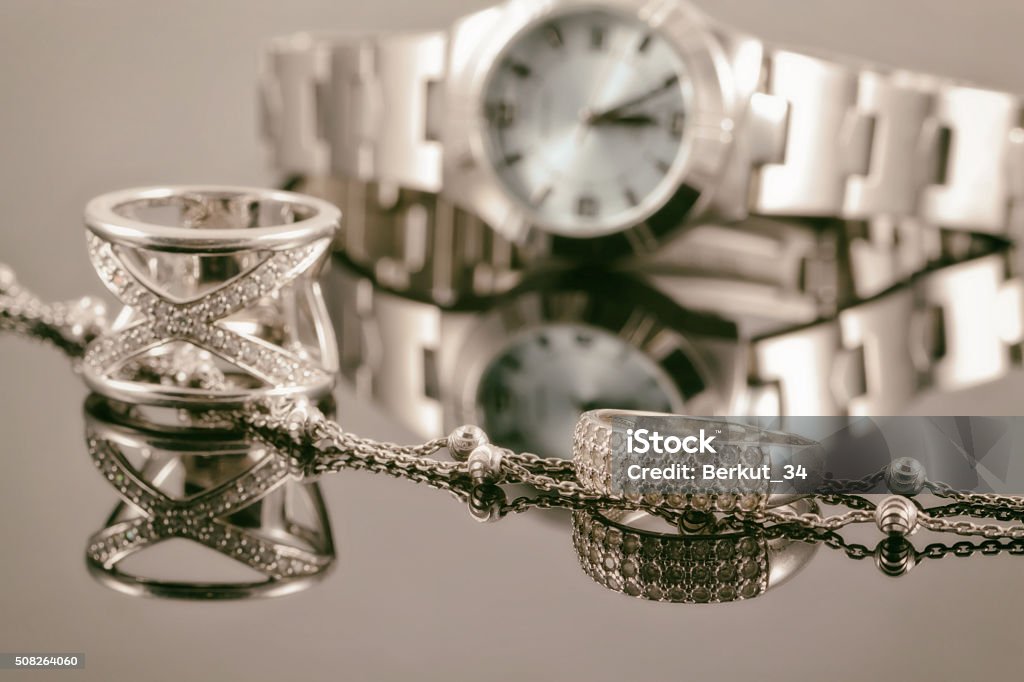 Silver rings and silver chain on background of women's watch Silver rings of different styles and silver chain on the background of reflections women's watches Jewelry Stock Photo