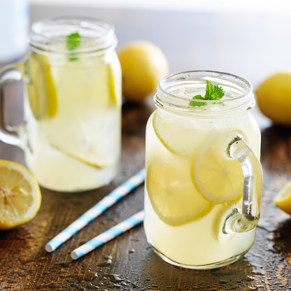 lemonade in jar with ice and mint shot close up with mint garnishes and paper straws