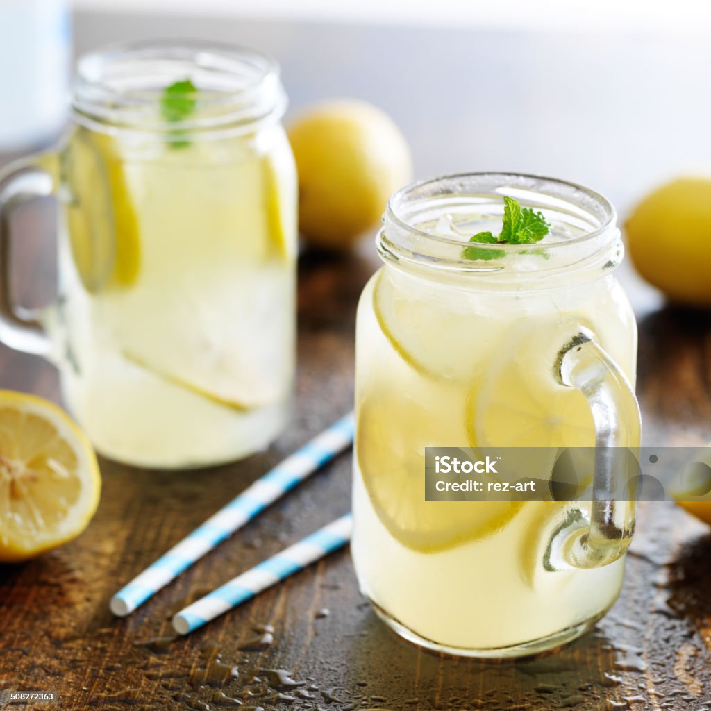 lemonade in jar with ice and mint lemonade in jar with ice and mint shot close up with mint garnishes and paper straws Lemonade Stock Photo