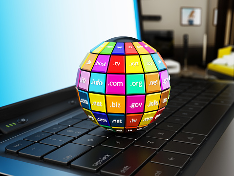 Globe with multi colored parts where domain names are written on laptop computer keyboard