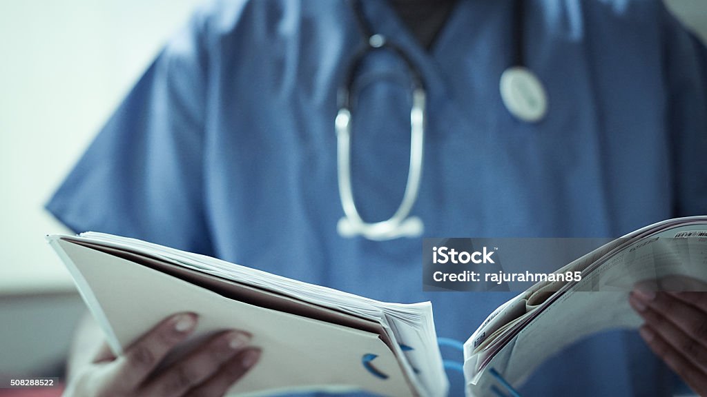 Doctor With Stethoscope And Files A doctor with a Stethoscope around his neck looking at a patients file. NHS Stock Photo