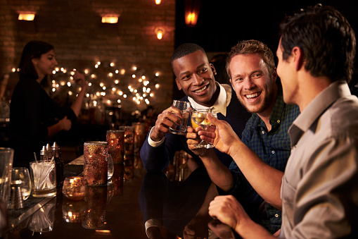 Hombre amigos mientras disfruta de un coctel en el Bar por la noche photo