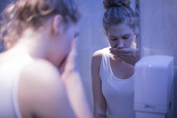 Girl in bathroom Worried girl standing in front of mirror bulimia stock pictures, royalty-free photos & images