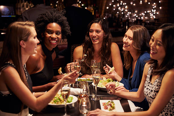 gruppe von weiblichen freunde genießen mahlzeit in restaurant - freundinnen stock-fotos und bilder