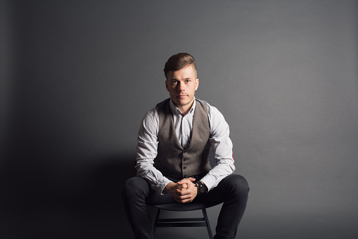 Studio portrait of a young caucasian man sitting in a chair.