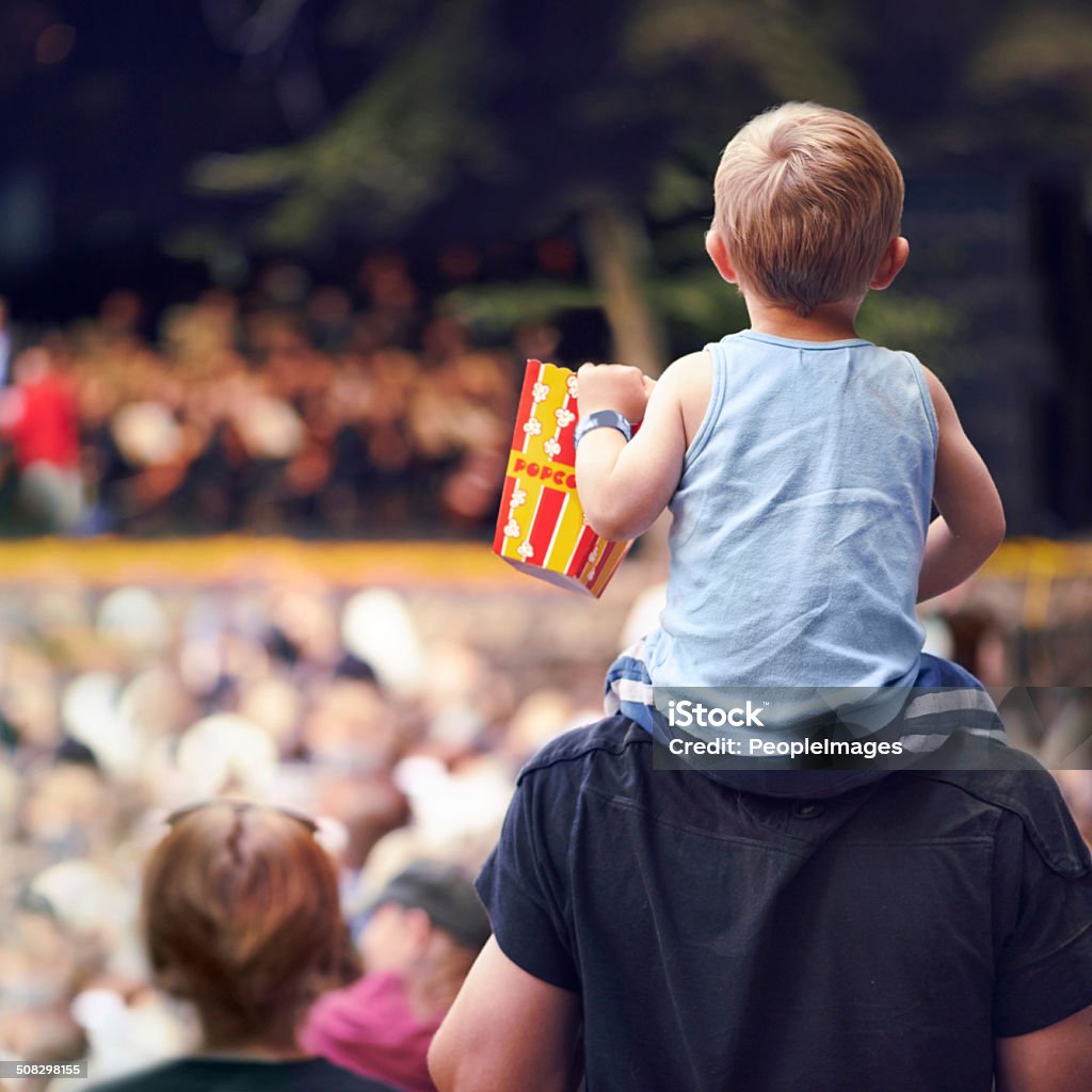 Snacks and entertainment Rearview shot of a young boy sitting on his father's shoulders at an outdoor festival Child Stock Photo